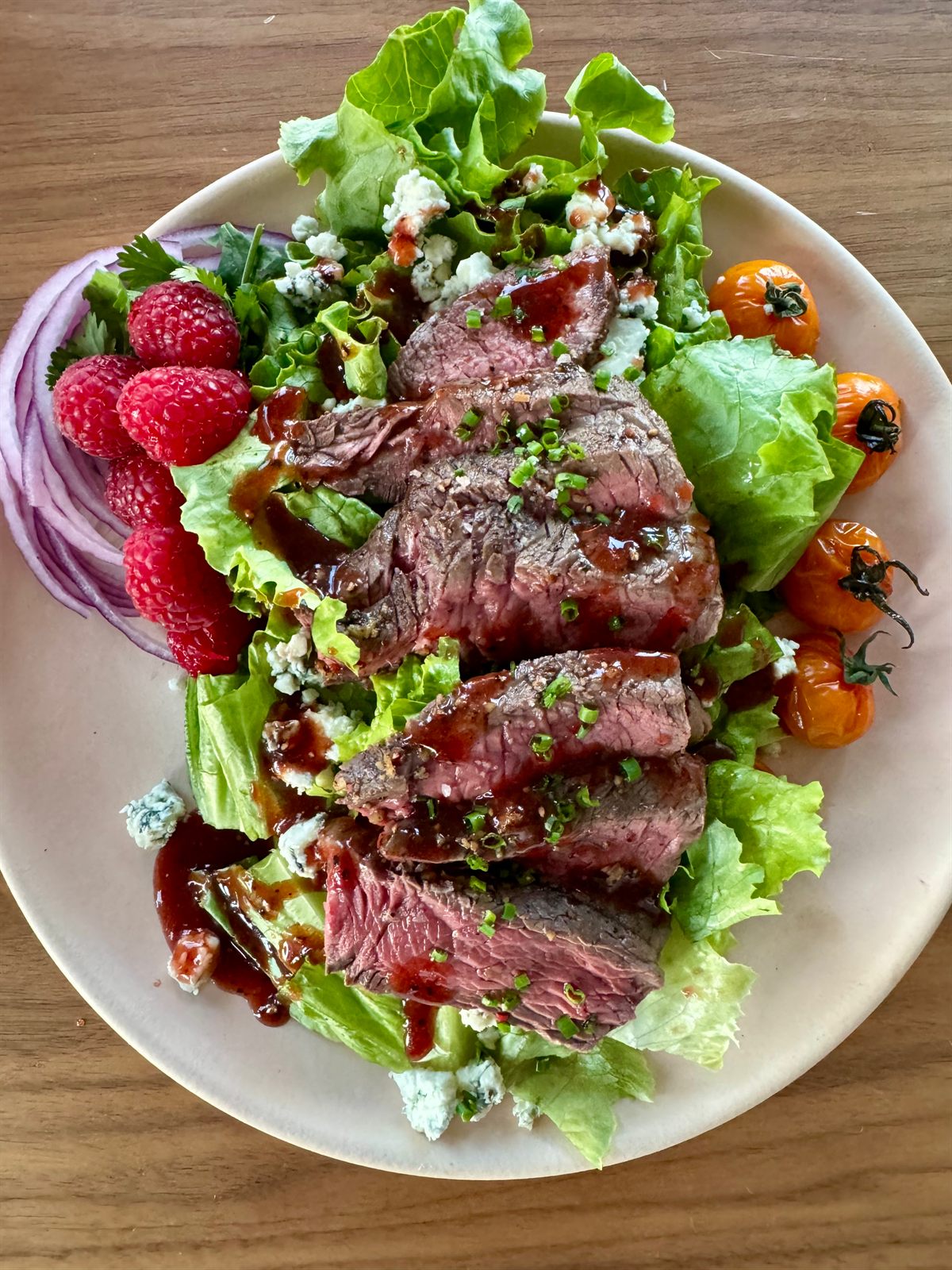 Sliced seared steak salad with raspberries, cherry tomatoes and blue cheese