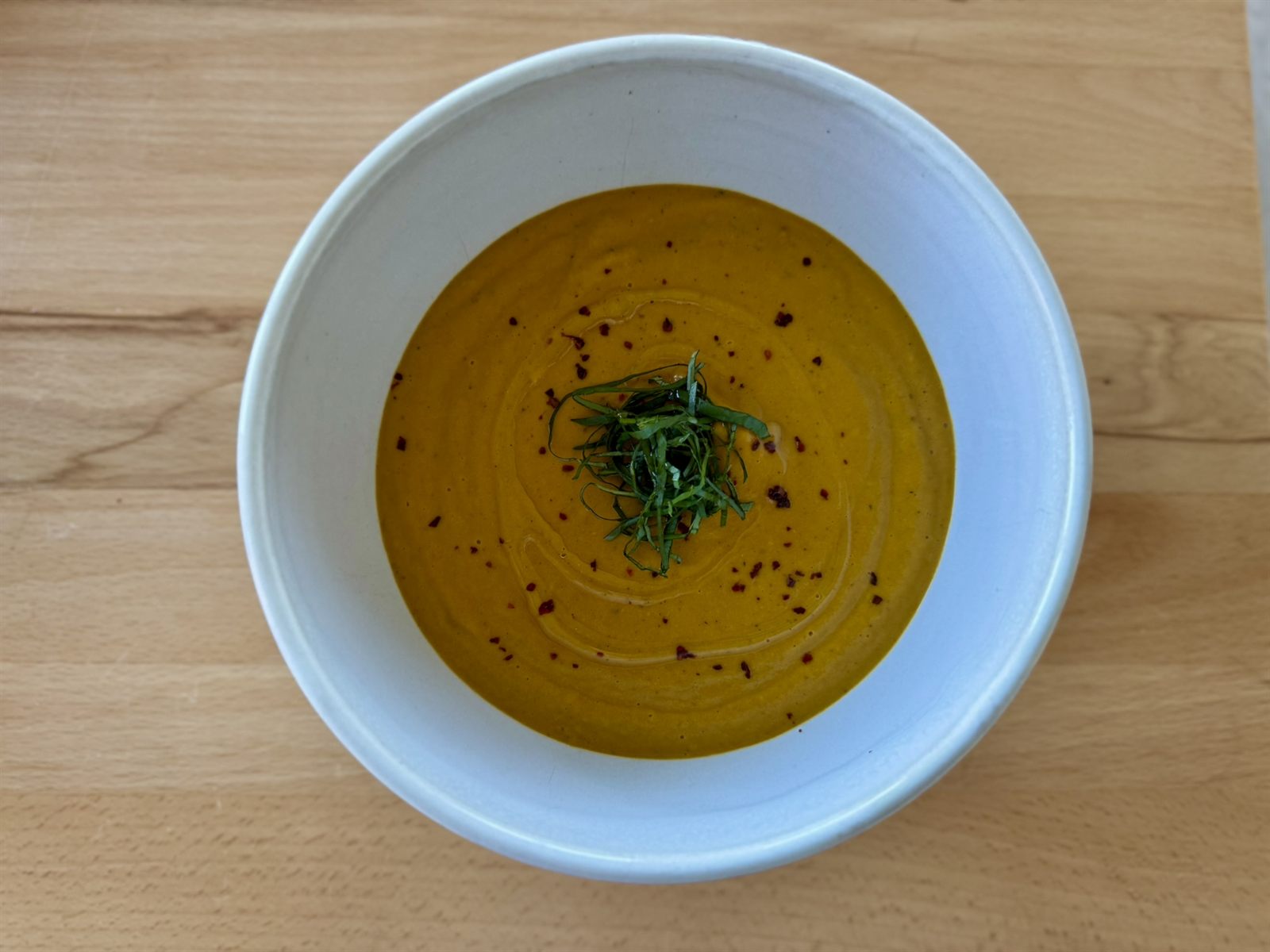 Bowl of golden squash soup with herbs and olive oil