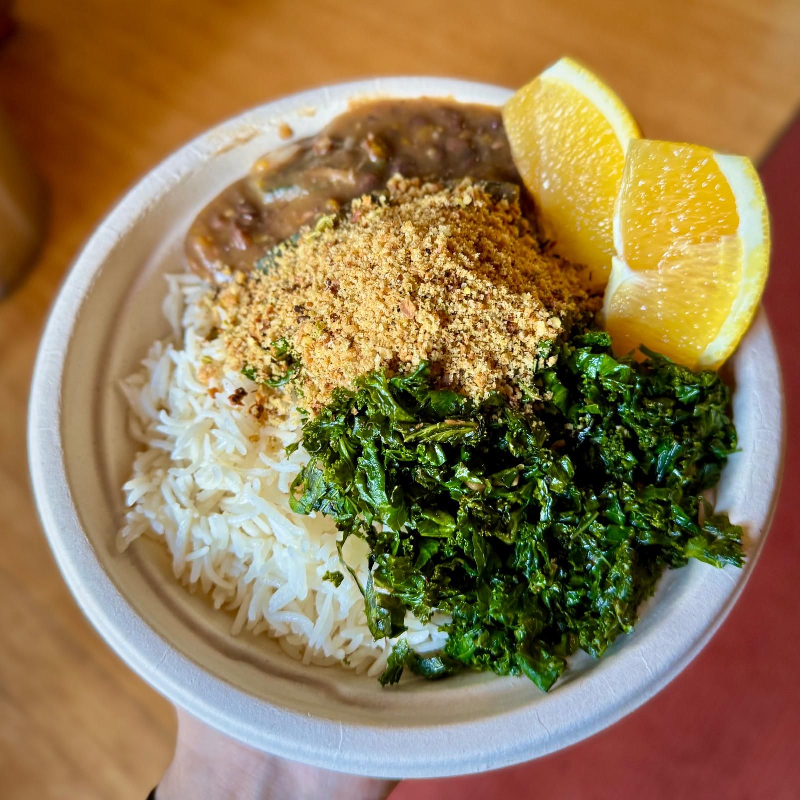 Bowl of white rice, beans, sautéed greens and toasted farofa with lemon wedges
