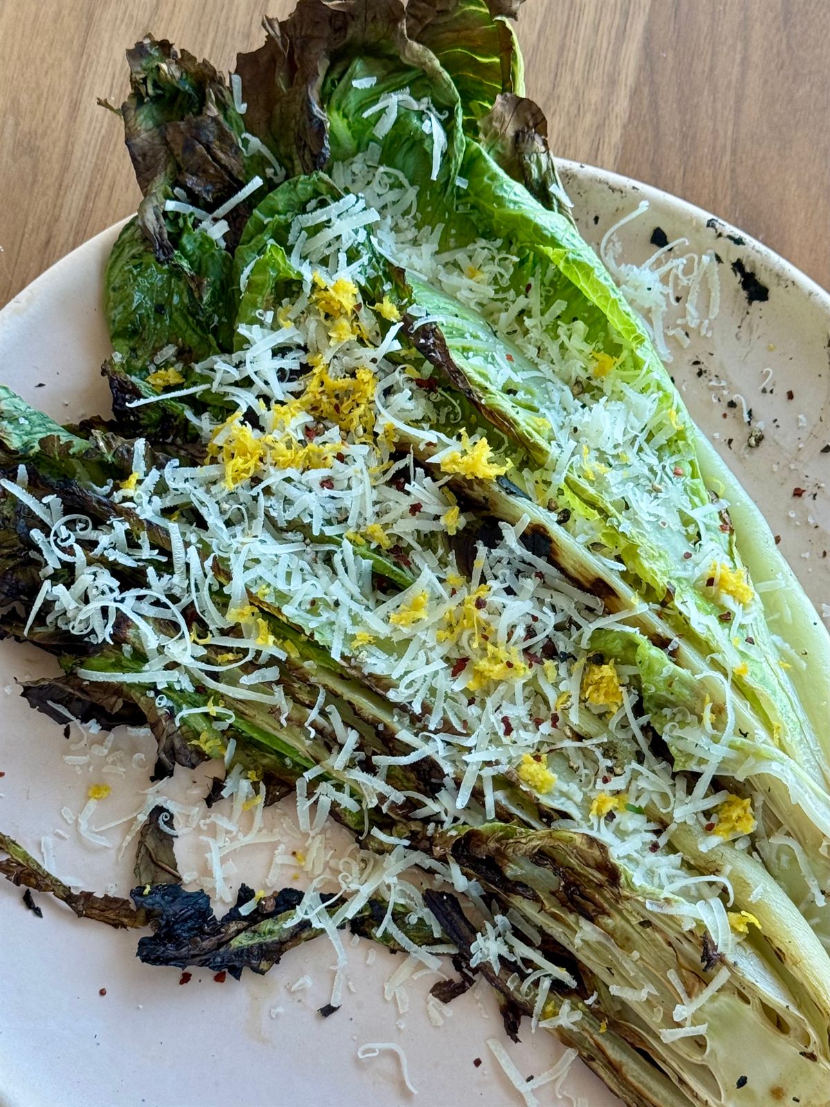 Charred romaine heart finished with grated cheese and lemon zest