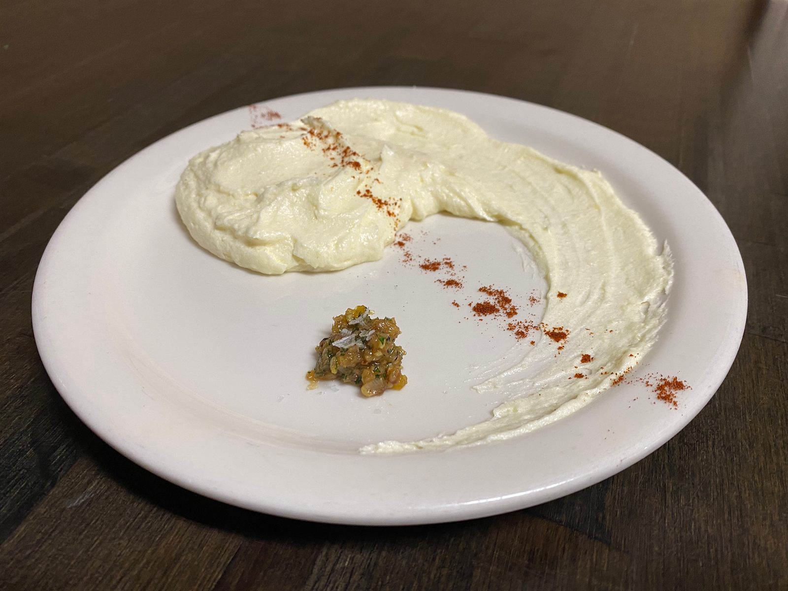 Whipped cream sauce with a spoonful of relish and chili flakes on a white plate