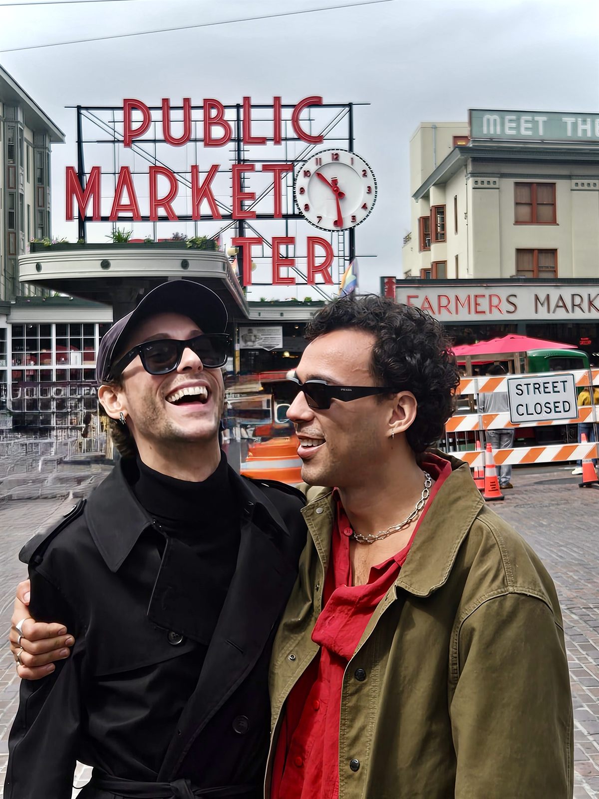Two people laughing in front of the Pike Place Market sign in Seattle