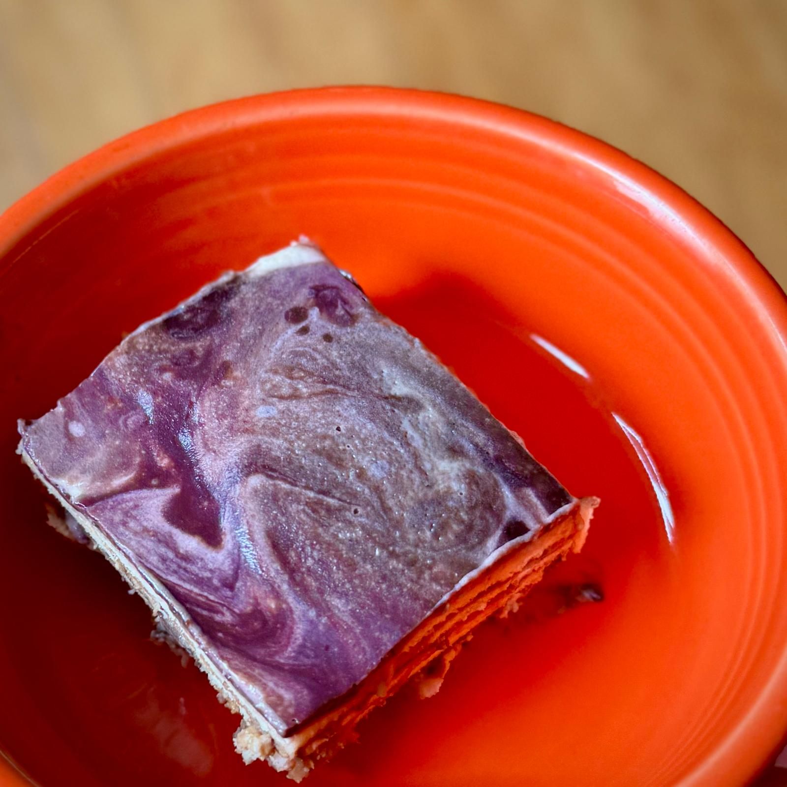 Layered dessert with a purple swirl on an orange plate